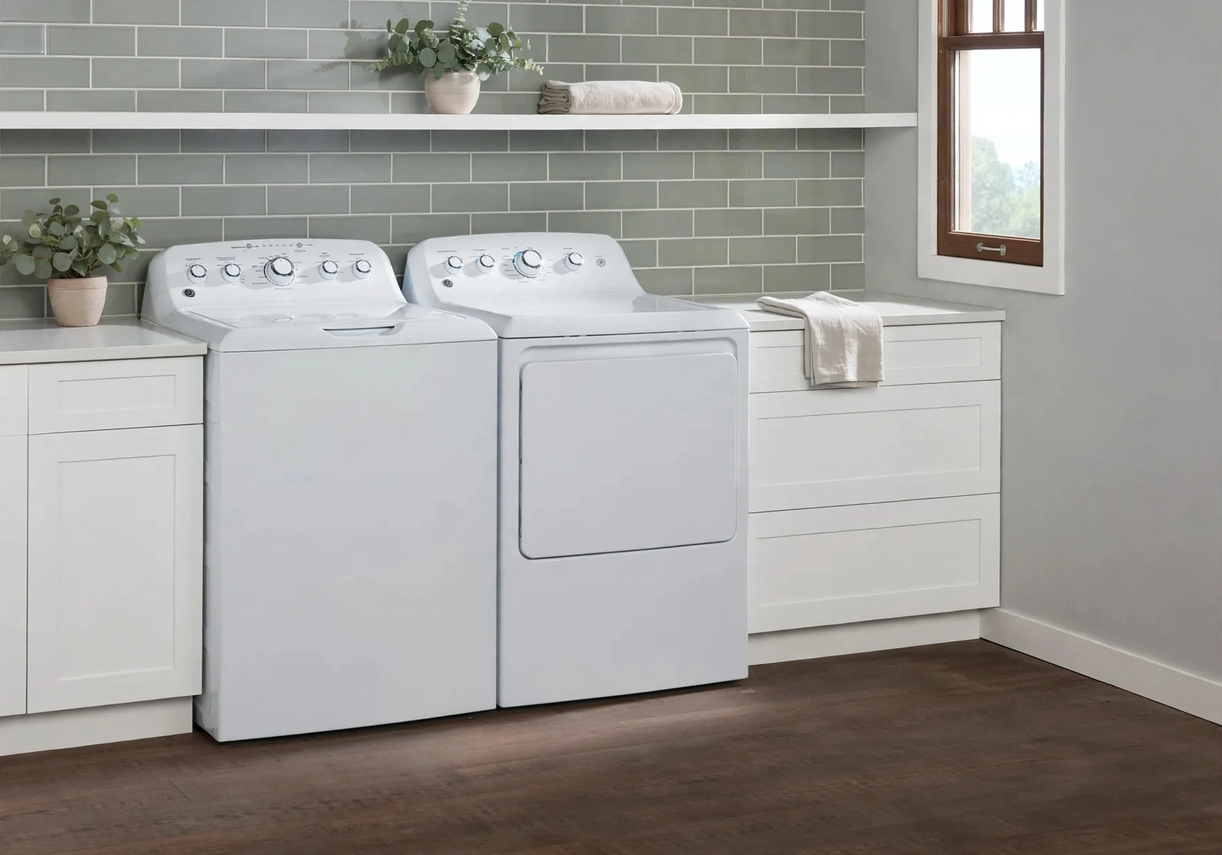 A white GE-style top-load washer and dryer set in a laundry room with sage-green tile